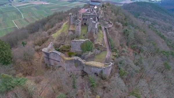 Die Madenburg wurde in Spornlage auf einem in die Rheinebene vorspringenden Felsausläufer des Rothenbergs erbaut. Die von Wald umgebene Ruine liegt etwa 250 m oberhalb der Rheinebene und dem Weindorf Eschbach. Luftbildansicht der Madenburg aus Norden