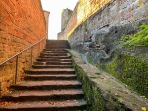 Ab dem Unteren Burgtor führt eine neue Treppe zur Oberburg. Die links zu sehende, 4m hohe, Ostwand mit ihrem hammergerechten Kleinquadermauerwerk ist nur im unteren Bereich spätmittelalterlich. Oberer Bereich der Felsentreppe zur Oberburg mit Wasserrinne