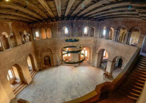 Der sog. "Kaisersaal" nimmt nahezu die gesamte trapezoide Grundfläche des Palas ein und reicht über 2 Geschosse. Der Palasbau folgt dem Aufbauplan von Rudolf Esterer von 1938 und hat mit dem historischen Bauzustand nicht mehr viel zu tun. Der Palas ist quasi ein kompletter Neubau. Das Panoramafoto zeigt den heutigen Zustand in der Übersicht Panoramaschwenk durch die große Halle des neuzeitlichen Palas auf Burg Trifels
