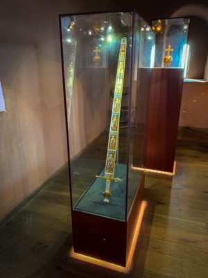 Das Reichsschwert gehörte zu den Reichskleinodien der römisch-deutschen Könige und Kaiser des Heiligen Römischen Reiches. Das Schwert überreichte der Papst dem römisch-deutschen Kaiser bei seiner Krönung als Zeichen der weltlichen Macht, die er aus der Hand Gottes erhält. Beim anschließenden Auszug aus der Kirche wurde es dem neuen Kaiser vom Schwertführer mit der Spitze nach oben als Zeichen der weltlichen Macht und Gewalt vorangetragen. (Quelle: Wikipedia) Replik Reichsschwert auf Burg Trifels