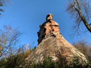 Der Besucher des Trifels kommt auf seinem Weg an dem unten glatt abgearbeiteten, oben kantigen, Felsenriff vorbei, das die Burg trägt, ohne sie aber von hier aus bereits sehen zu können. Südseite des den Trifels tragenden Felsenriffs auf dem Sonnenberg