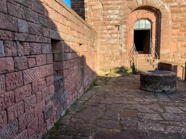 ln die ungefähr 4 m hohe äußere Umrahmung des Turmeingangs ist ein mit knapp 3 m Höhe wesentlich kleineres Rundbogenportal eingelassen. Zwischen Wachthaus und Turm liegt ein kleiner Hof, der seit den frühen 1960er Jahren (wieder) von Mauern eingefasst ist, die auf der Westseite eine Höhe von über 3 m hat . Im Hof ragt die Replik einer Entnahmeröhre einer aufgelassenen Zisterne hervor, die mit Erbauung des Brunnenturms im 13. Jh. obsolet wurde. Blick vom kleinen Hof auf das Rundbogenportal des Hauptturms