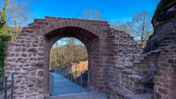 Das Äußere Burgtor wurde während der Sanierungsarbeiten in der letztem Dekade neu erbaut. Rechts ist eine Nische für den Torwächter zu sehen. Die Innenseite des Tors lässt m.E. wichtige Fragen offen. So ist nicht erkennbar, ob der tornahe Bereich der Brücke über den Halsgraben als Zugbrücke ausgeführt war, so wie wir es von Landeck kennen. Ansonsten hätte die Vertiefung des westlichen jüngeren Halsgrabens wenig Sinn gemacht. Die Führung einer Kette und die Platzierung einer Zugvorrichtung müssen im Spekulativen bleiben. Rekonstruktion des Äußern Tores von 2020 mit Wächterkammer