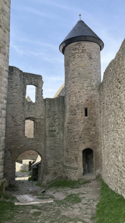 Neben den Resten des früher dreigeschossigen Torhauses schließt sich ein schlanker Treppenspindelturm an. Rundbogentor im Torhaus und schlanker Treppenturm